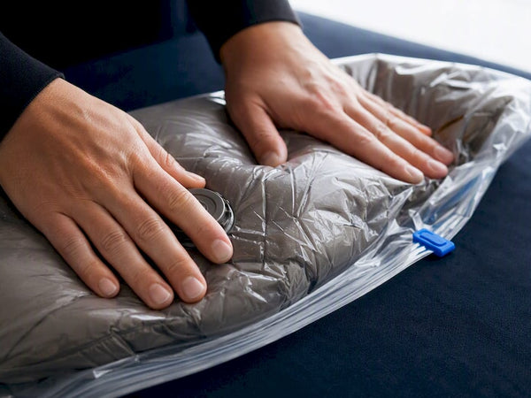 Hands compressing a puffer jacket for travel