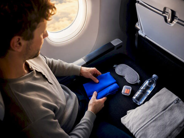 Long flight essentials arranged in airplane seat