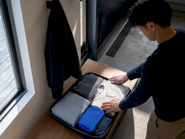 Hands arranging clothes for carry-on travel